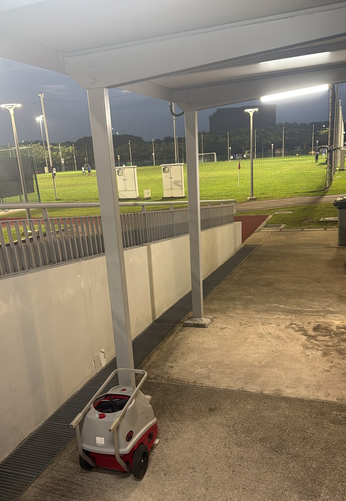 Tennis ball machine moved under court-side shelter during a rain shower in Singapore
